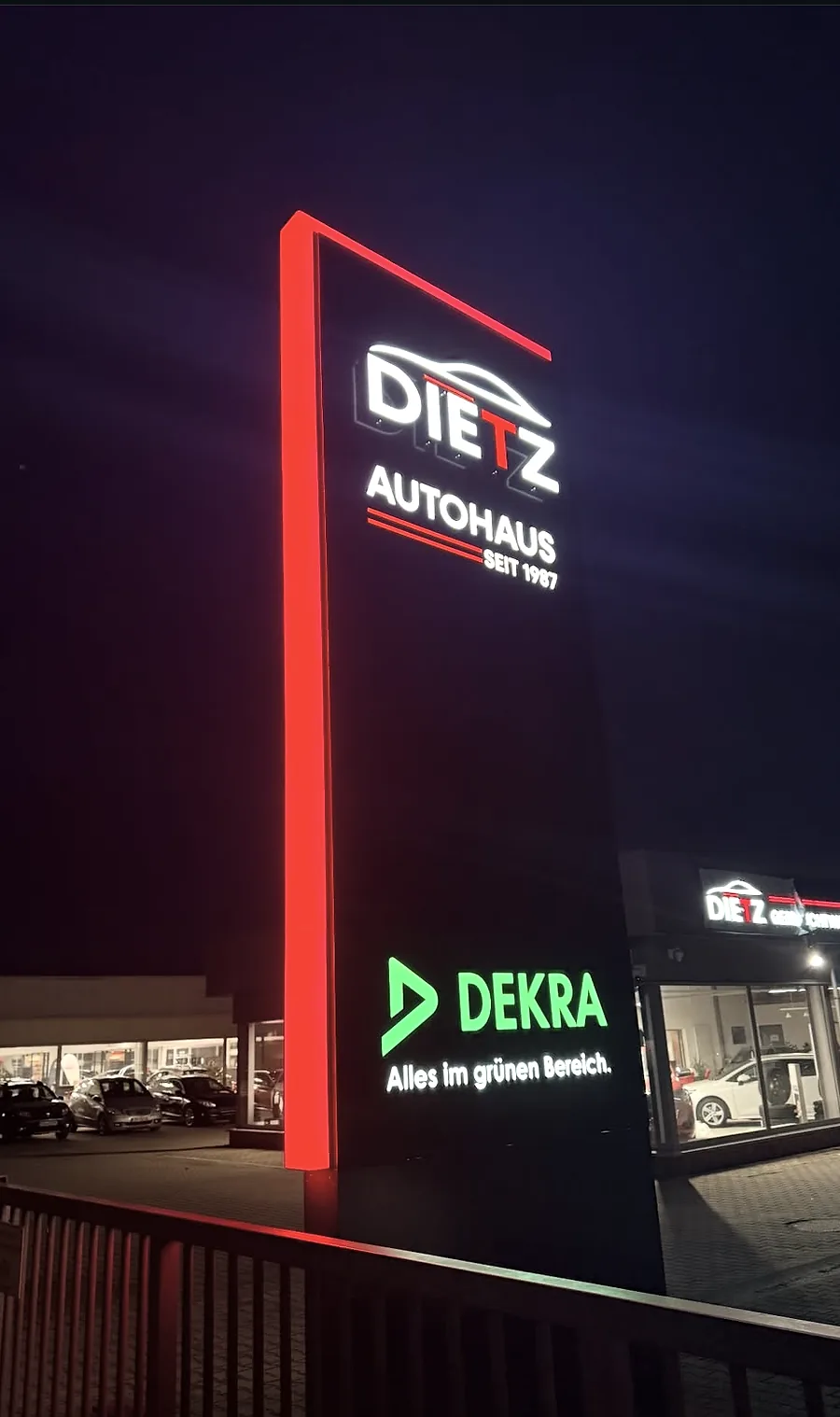 Beleuchteter Werbepylon und Fassadenwerbung eines Autohauses bei Nacht