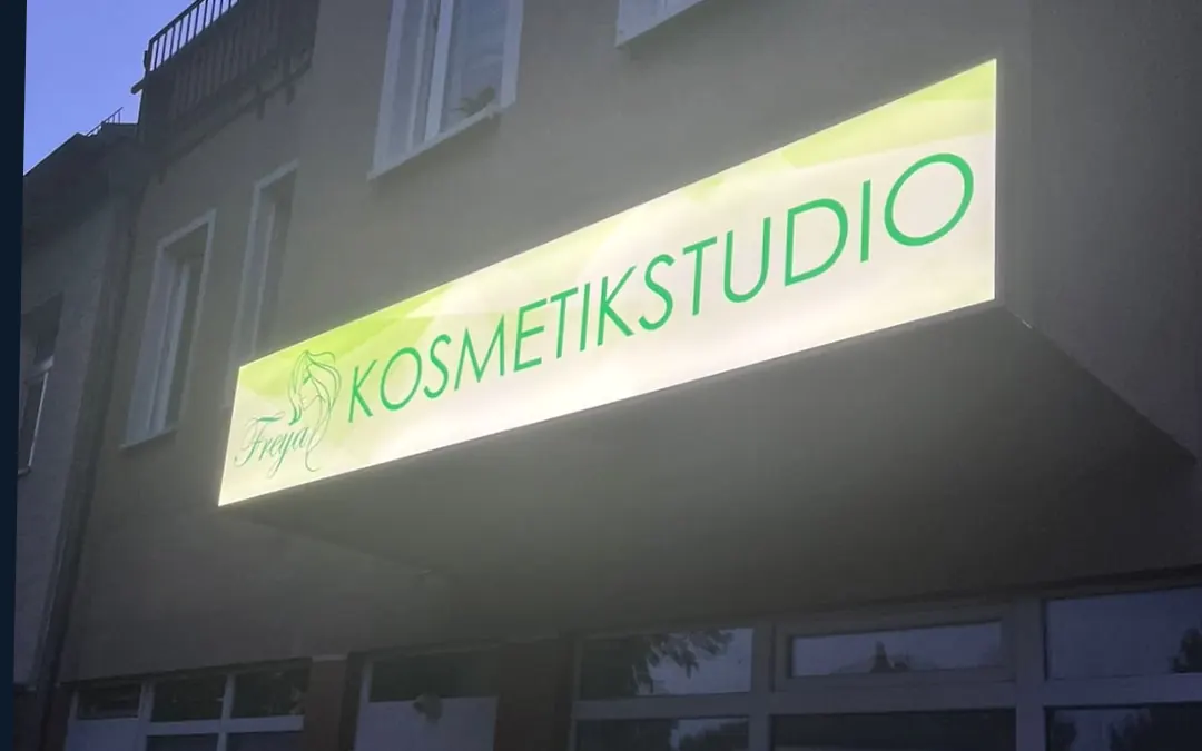 Gleichmäßig beleuchteter Leuchtkasten eines Kosmetikstudios an einer Fassade